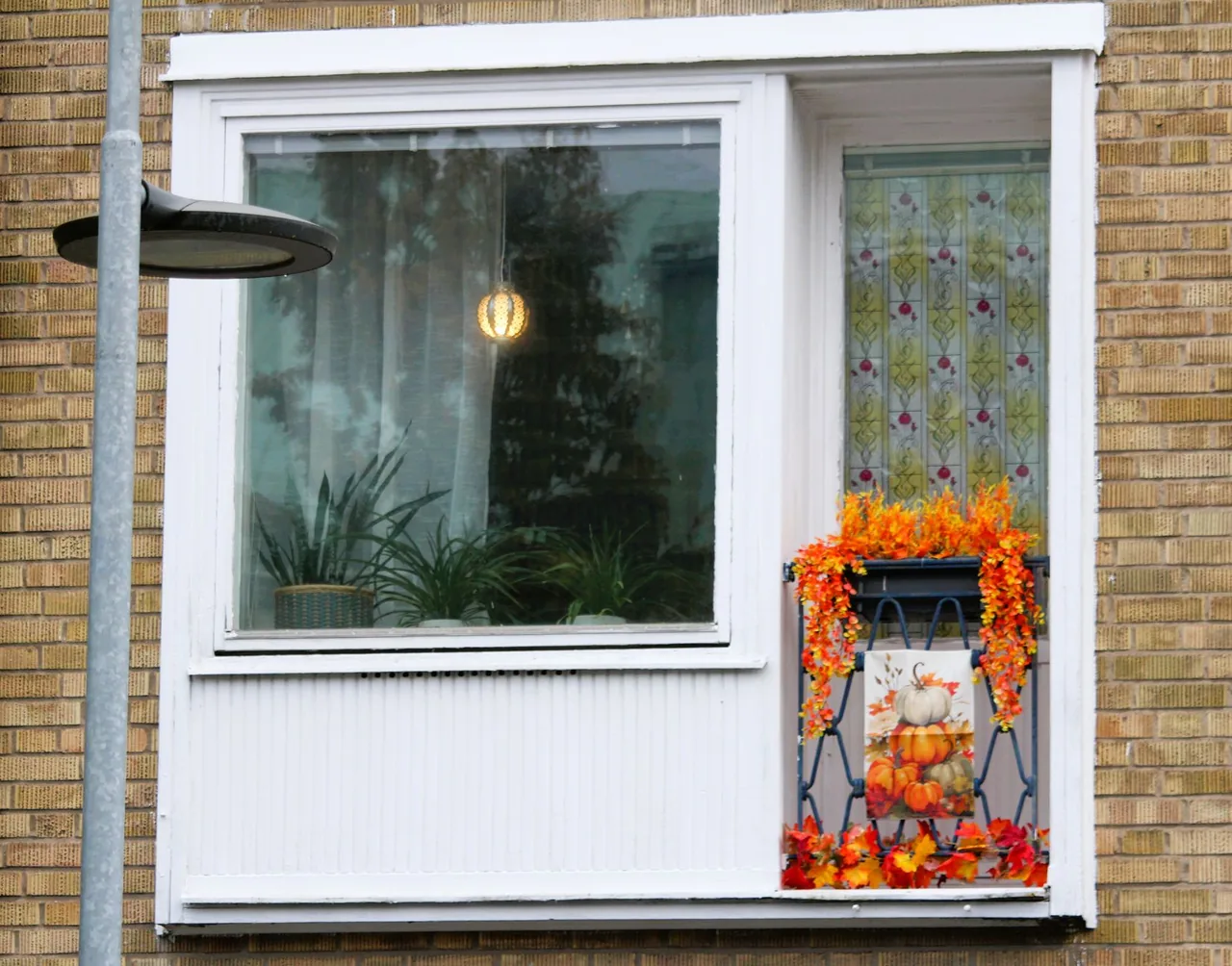 Jesienne dekoracje balkonu — skrzynka z wrzosami, dynie ozdobne i lampion